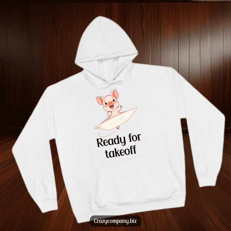 Funny hoodie graphic featuring a cheerful piglet riding a huge, unstable paper airplane with evident delight.